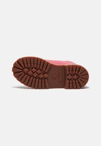 Suola di stivale Timberland in gomma marrone, con profondi motivi di battistrada e un logo, con bordi superiori rosa visibili in cima.