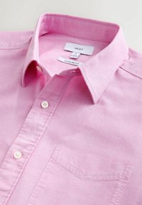 Helles rosa Hemd aus Baumwolle mit normaler Passform, das über einen spitzen Kragen, eine einzelne Brusttasche und weiße Knopfverschlüsse verfügt.