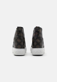 Sneaker nere con tomaia in pelle testurizzata, caratterizzate da un motivo con logo marrone, suola in gomma bianca e linguette sul retro.