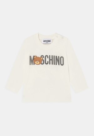 Camiseta blanca de manga larga con un gráfico de oso pardo y el texto "MOSCHINO" en negrita negra. Fabricada con suave tela de algodón y con cierres a presión.