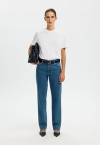 Valge puuvillane T-särk, sinised sirge säärega teksad, must nahast käekott, mustad terava ninaga kontsakingad. Lihtne disain, puhtad jooned ja neutraalsed värvid.