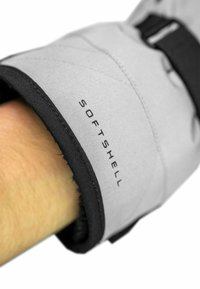 Graue Softshell-Handschuhe mit einem schwarzen Bund und Nähten. Der Bund hat den Aufdruck "SOFTSHELL", der ein strukturiertes, langlebiges Material zeigt.