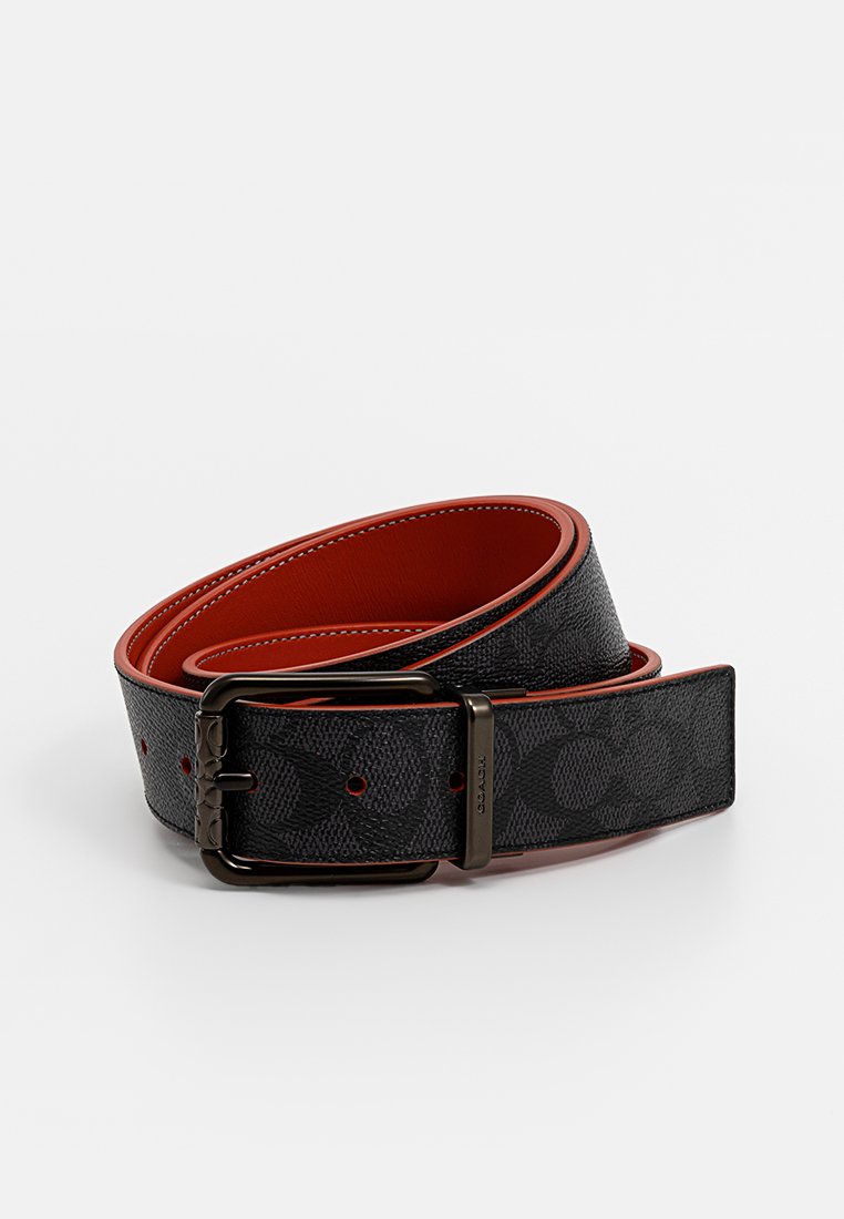 Schwarzer strukturierter Ledergürtel mit rotem Rand und Innenfutter, Schnalle in Gunmetal-Farbe und dezent eingepreßtem Muster, auf einem weißen Hintergrund gewickelt.