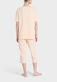 Set di pigiama pesca composto da una maglietta a maniche corte e pantaloni accorciati, realizzato in un tessuto morbido con una finitura liscia. Design semplice e rilassato.