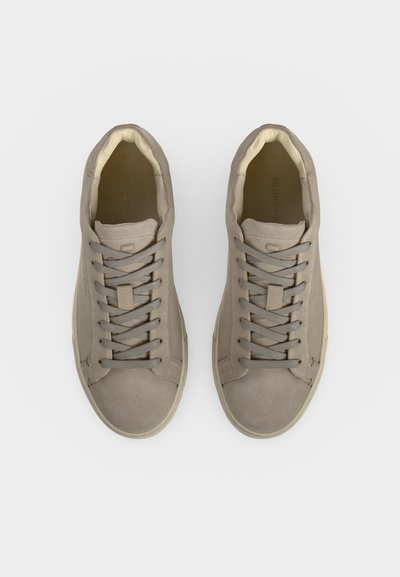 Paire de baskets en daim brun clair avec des lacets assortis, des bouts ronds et des collets intérieurs rembourrés, vues de dessus sur fond blanc.