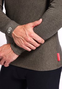 Langermige shirt in donkergroene stof met een gladde textuur; beschikt over een logo op de manchette en een rode label op de zijnaad.