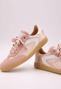 Rosa mockaskor med vita läderdetaljer, rund tå, snörning och gummisulor med scallopade kanter samt varumärkeslogotyp på tungan.