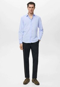 Lichtblauw langsliever shirt met knopen, zwarte broek en bruine veterschoenen. Synthetische textuur, slim fit ontwerp en subtiel kleurcontrast.