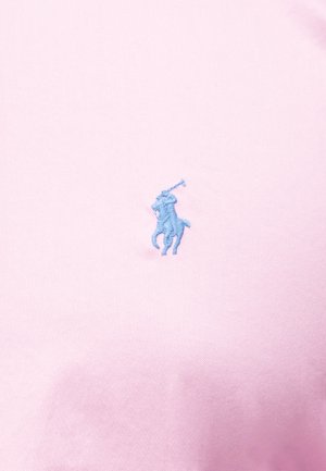 Lichtroze stof met een kleine lichtblauwe geborduurde polospeler te paard met een geheven mallet.