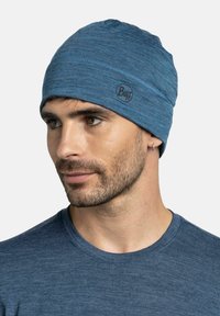 Blue knit beanie made from soft, textured fabric. Features a Buff logo on the side, with a snug fit and simple, seamless design.