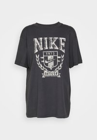 T-shirt en coton noir avec un col rond et des manches courtes. Présente un graphique gris avec "NIKE", "1972" et "OREGON" dans un imprimé usé.