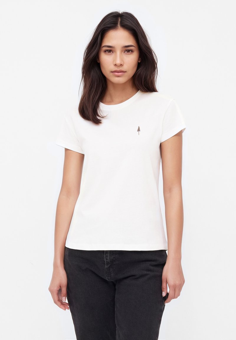 Witte katoenen T-shirt met korte mouwen, voorzien van een klein bruin boompje-embleem op de linkerborst, gecombineerd met donkere jeans.
