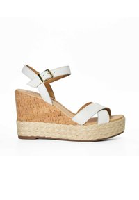 White wedge sandal with cork-textured heel, braided jute platform, and adjustable ankle strap featuring a gold buckle detail.