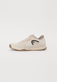 Sneaker med en beige mesh-overdel, lysebrune snørebånd, svarte aksenter og en teksturert gummisåle. Har en polstret design for støtte.