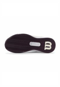 Suela de zapatilla de tenis en blanco y morado con un patrón de tracción en zigzag. Presenta un logotipo circular y el nombre de la marca "Wilson" en un pequeño óvalo.