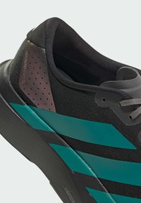 Black athletic shoe with a textured upper, teal stripes, and a matte black sole. Features a padded collar and perforated detailing.
