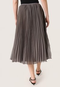 Plissé midi-jurk in een zachte grijze stof, met een gestructureerde afwerking. Elastische tailleband en vloeiende silhoeët met een doorschijnende overlay.