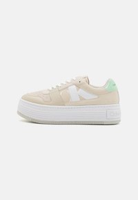 Sneaker platform Calvin Klein con tomaia sintetica beige, branding bianco e accento verde menta sul tallone. Suola in gomma testurizzata.