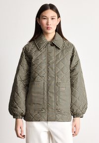 Prošívaná péřová bunda v hnědém vzoru psa zub, s velkým límcem, elastickými rukávy a dvěma předními kapsami. Hladká, polstrovaná textura.