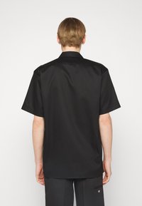 Zwart shirt met korte mouwen, met een gladde textuur, klassieke kraag en een rechte snit. Geen zichtbare patronen of versieringen.