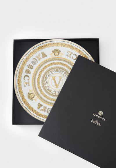 Dekoracyjny talerz Versace z białej porcelany ze złotymi wzorami i logo, zapakowany w czarne pudełko prezentowe z złotym logo.