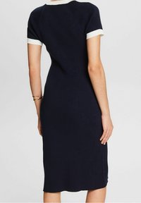 Robe côtelée marine à manches courtes avec un bord blanc au niveau du cou et des manches ; design ajusté, longueur au genou. Texture lisse sur l'ensemble.