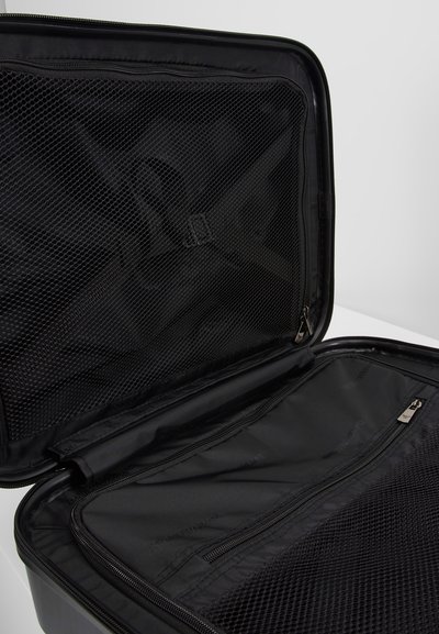 Bolsa de viaje negra con una cremallera abierta; el interior cuenta con bolsillos de malla y un compartimento plano con cremallera en un lado. Material suave y duradero.