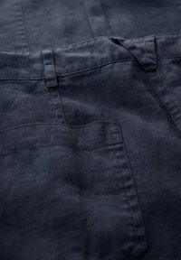 Dark blue linen pants, featuring a smooth texture, flat front pockets, and subtle stitching details. Clean lines with a tailored design.