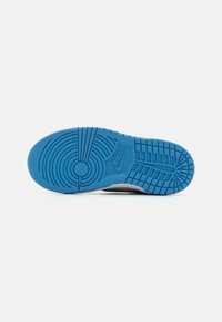 Podeszwa sneakersów Nike w niebieskiej gumie, z teksturowanym wzorem gripu zawierającym okrągłe i poziome rowki. Zawiera wzmocnioną strefę pięty.