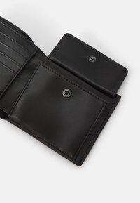 Portafoglio in pelle nera con scomparti per carte, tasca per monete e chiusura a scatto. La superficie liscia e i dettagli di cucitura precisi migliorano la funzionalità.