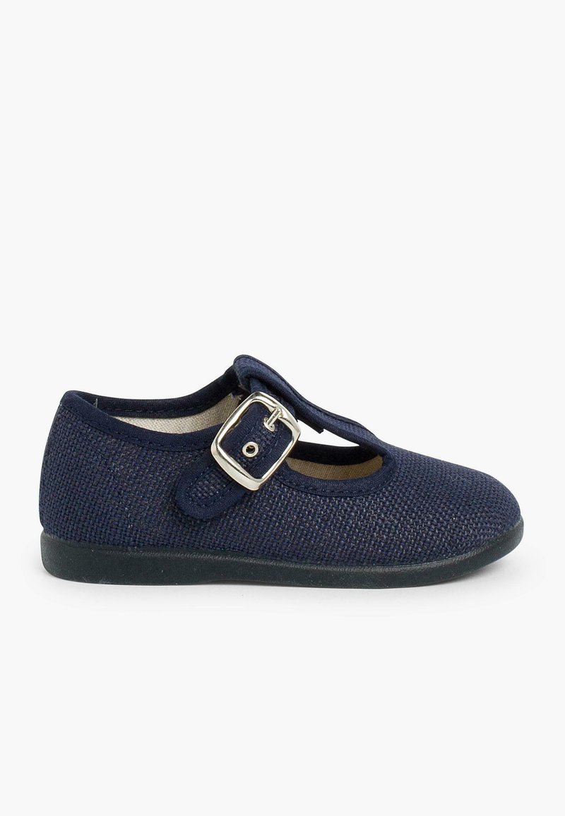 Zapato Mary Jane azul marino con textura trenzada, correa con hebilla, punta redonda y suela flexible de goma negra. Presenta un diseño con recortes.