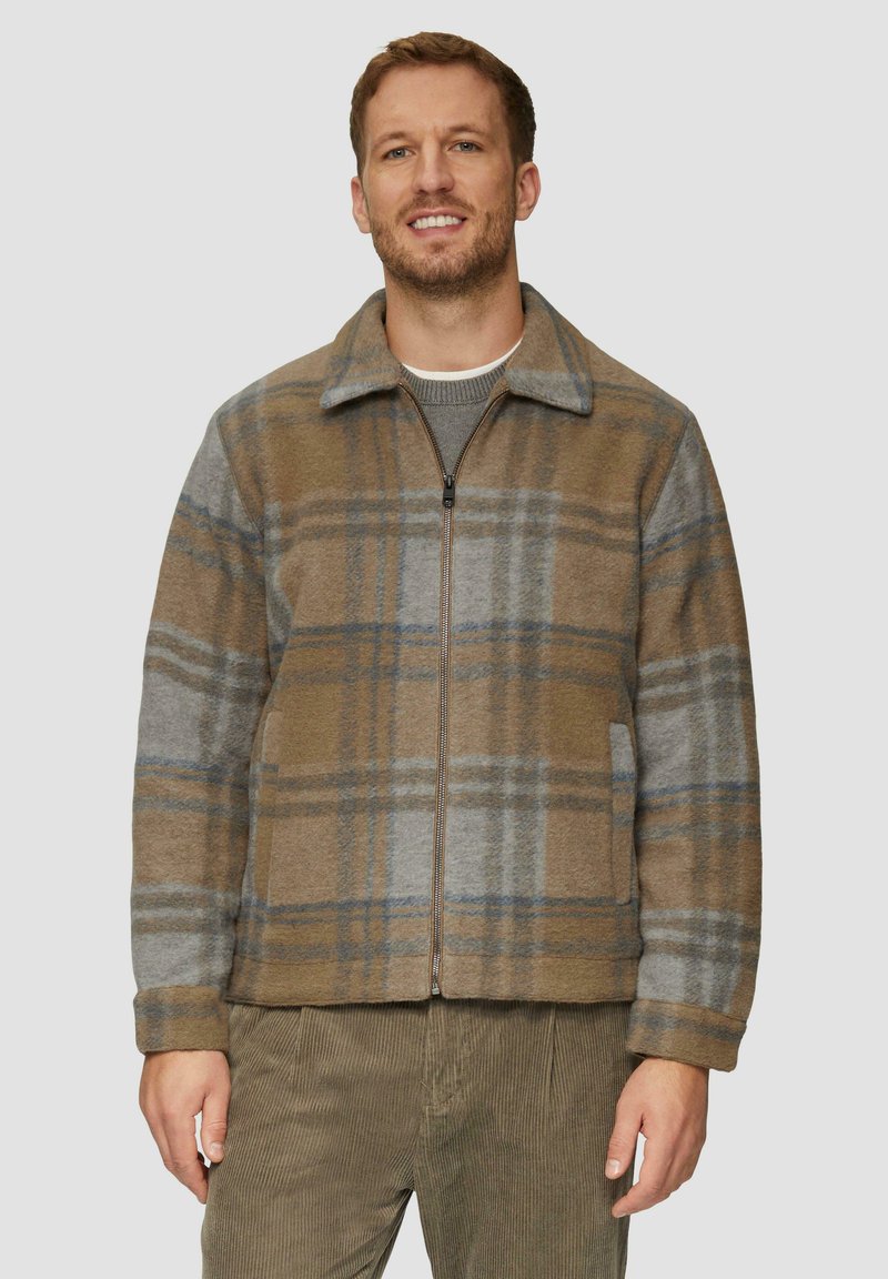 Bruin en grijs geruite fleece jack met rits, hals en zijzakken. Heeft een relaxte pasvorm en subtiele blauwe accenten.