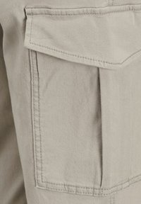 Beiga bomullscargobyxor med en stor, vinklad ficka på låret med sydda kanter och en smidig yta.