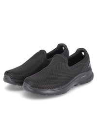 Schwarze Slipper aus Mesh-Stoff verfügen über eine strukturierte Oberfläche, eine gepolsterte Sohle und ein abgerundetes Toe-Design, das eine leichte Passform bietet.
