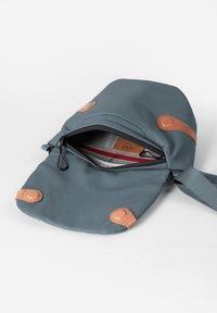 Blauwe schoudertas met bruine leren accenten, gedeeltelijk open om een grijze en rode binnenvoering en merklabel aan de binnenkant te onthullen.