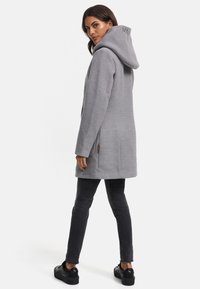 Grå huva jacka i ett mjukt tyg, med sidofickor, en hög krage och logotypdetaljer på huvan, kombinerad med svarta slim fit jeans.