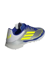 Sport shoe featuring a silver and navy design with bright yellow accents, textured synthetic material, and a cleated sole for traction.