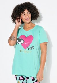 Mintgrøn t-shirt med rund hals, prydet med et pink hjerte design med et glitterende øje og "Happy" tekst i guld. Korte ærmer.