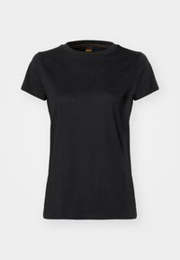 Melnā kokvilnas T-kreklā ar īsām piedurknēm, apaļu kakla izgriezumu un smalkiem rotājumiem uz krūtīm. Gluda tekstūra un brīvs griezums.