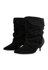 Mustad anteelja saapad, millel on lohisev disain, teravad varbad ja väike kitsenev kont. Omab pehmet tekstuuri ja peenet laine detaili ülevalt.