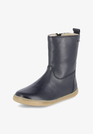 Botte mi-mollet en cuir noir avec semelle beige, fermeture éclair latérale, languette de traction et doublure polaire de couleur claire visible en haut.
