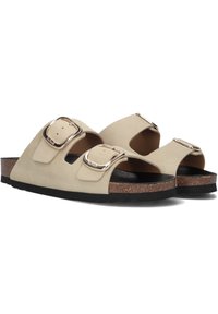 Beige leren sandalen van suede met twee verstelbare banden, zilveren gespen en een kurken voetbed. De zool is zwart met gestructureerde groeven voor grip.