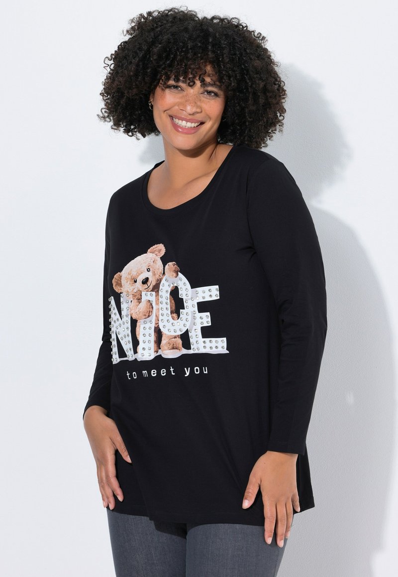 Czarna koszula z długim rękawem z grafiką misia i literami zdobionymi kryształkami układającymi się w słowo „NICE”, poniżej napis „miło cię poznać”.