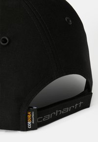 Crna kapa od izdržljivog materijala, s zakrivljenim vizirima, ventilacijskim rupama i CORDURA® oznakom sa strane. Logo "carhartt" u sivoj boji.