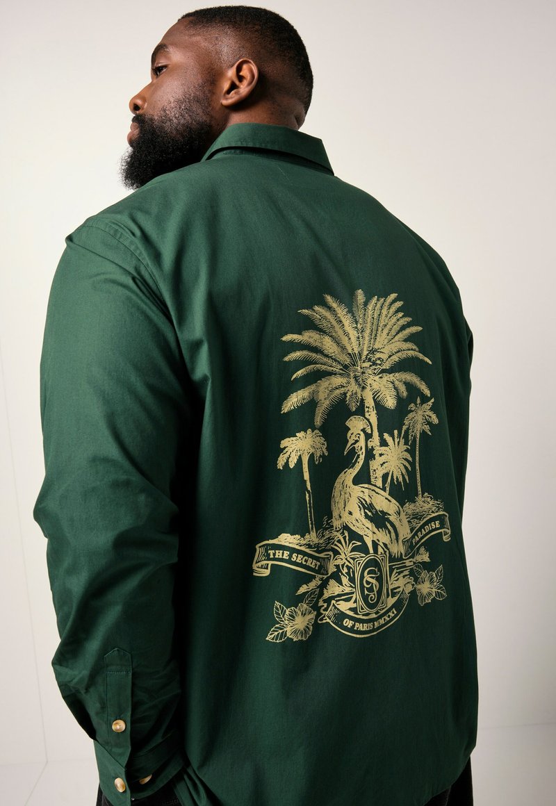 Grünes Button-up Hemd mit einem großen goldenen Palmen- und Vogelmotiv auf dem Rücken. Verfügt über goldene Knöpfe an den Manschetten und besteht aus glattem Stoff.