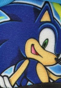 Tela azul con un personaje de dibujos animados que tiene ojos verdes y acentos negros, mostrando una expresión sonriente y una pose dinámica.