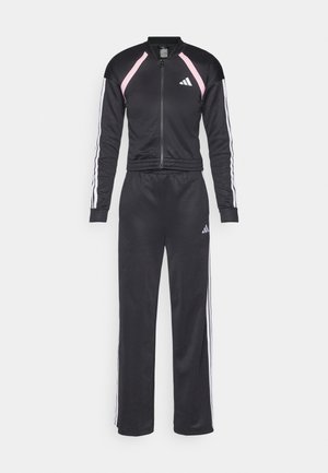 Compleu sport negru dintr-un material neted; are accente cu dungi roz și albe, jachetă cu fermoar și pantaloni tapered cu talie elastică.