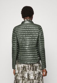 Zelená péřová bunda s úzkým střihem, lesklým povrchem a horizontálním prošíváním. Má límec a malé logo na lemu.