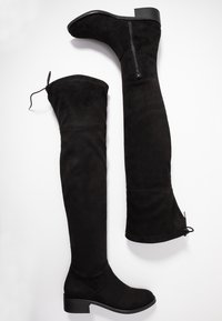 Schwarze Wildleder-Stiefel über das Knie mit Blockabsatz, ausgestattet mit einem seitlichen Reißverschluss und einem verstellbaren Band oben für einen figurbetonten Look.