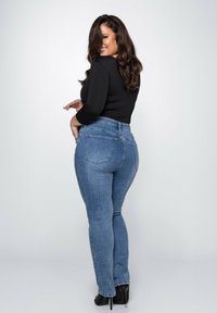 Schmale Denim-Jeans in heller Waschung mit hoher Taille, fünf Taschen und einer vorteilhaften Passform. Kombiniert mit einem schwarzen Langarmoberteil.